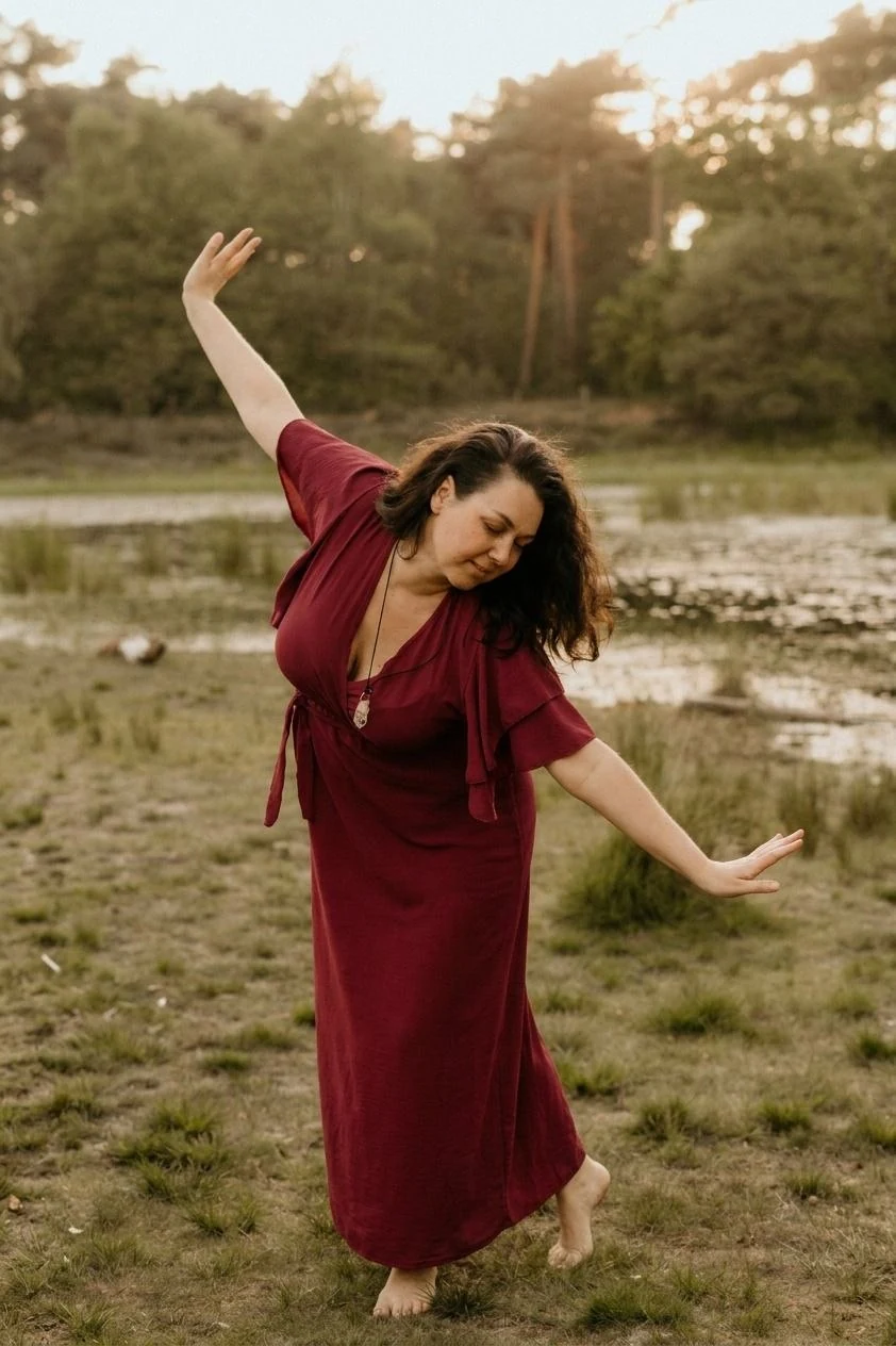 Deborah in een wijnrode jurk, bewegend in de natuur bij het water