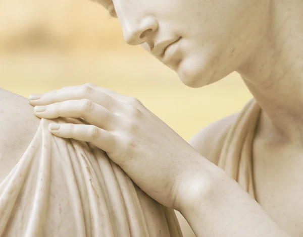 Een marmeren hand rust zacht op de schouder van een andere vrouw